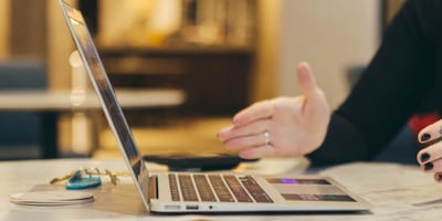 Foto van iemand die iets uit lijkt te leggen, laptop op tafel